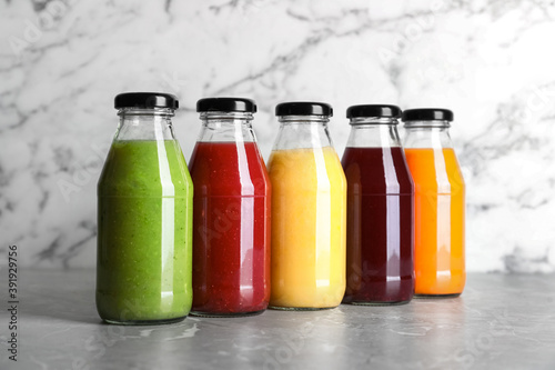 Bottles with delicious colorful juices on marble table