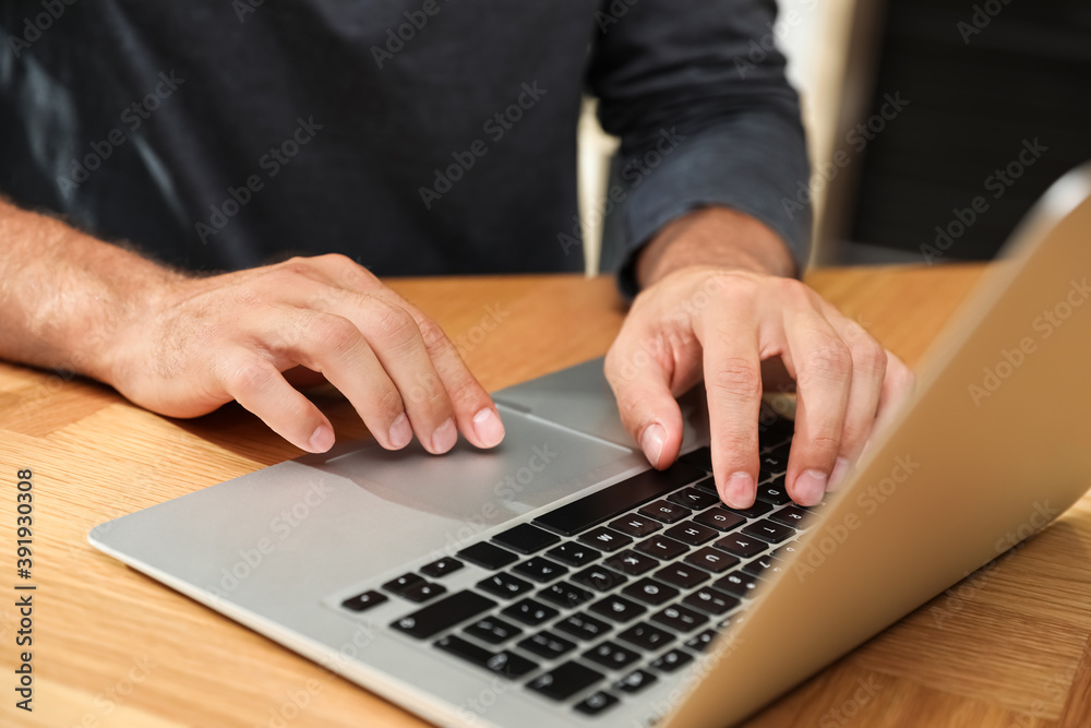 Man using laptop for search at wooden table, closeup