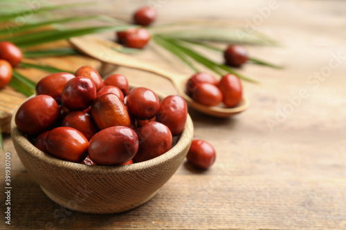 Palm oil fruits in bowl on wooden table, closeup