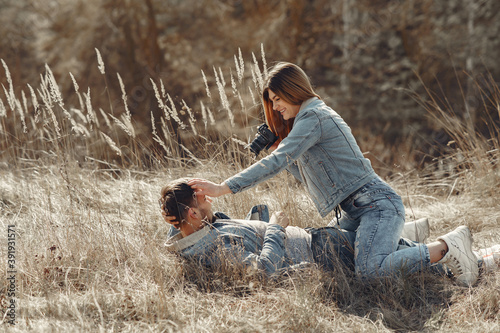 Woman in a jeans clothes. Couple in a spring field. Girl makes a photo to her boyfriend.