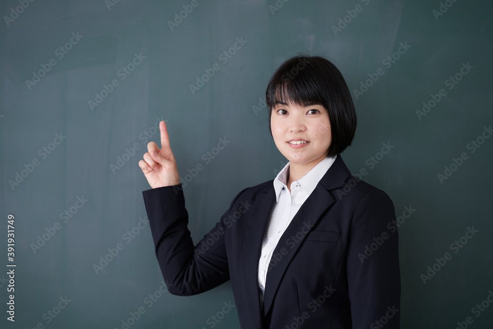 教室で黒板を指す日本人女性教師