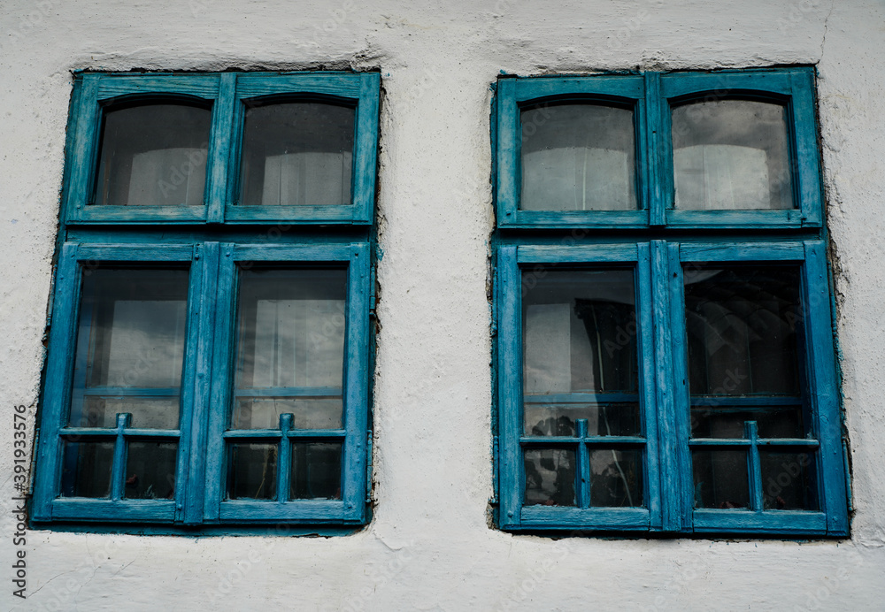 old blue windows to a house painted white
