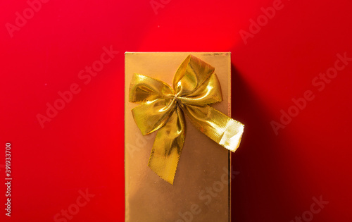 Gift in a golden package with a bow on a red background