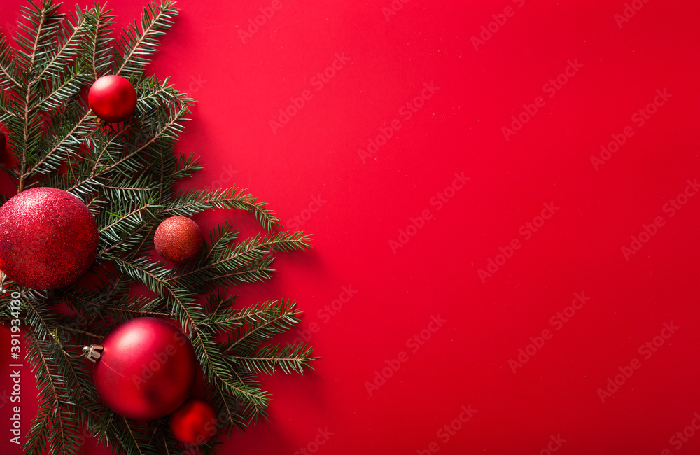 Christmas tree branches and New Year red toy balls on a red background.