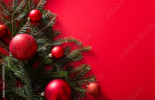 Christmas tree branches and New Year red toy balls on a red background.