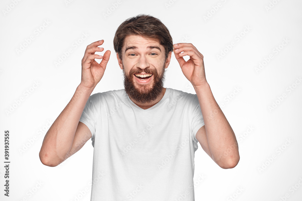 Bearded man in white t-shirt gesture with hands emotions light background Bearded man in white t-shirt gesture with hands emotions light background