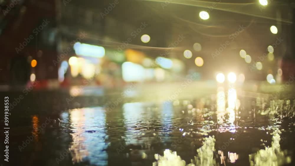 London bus passing behind rain falling in a puddle super slow motion night