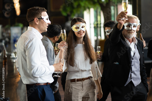 Masquerade party. Beautiful women and men wearing fantasy mask. Company employee enjoy drinking in mask party  together indoors celebration