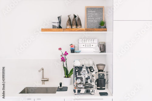 Kitchen countertop front flat view of home espresso machine styled as cafe bar with menu for espresso, cappuccino, latte, wooden trays for beans bags. © Maridav