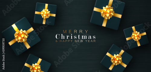 Gift boxes are on the boards. Merry Christmas and happy New year. Realistic background with voluminous green gifts tied with a gold ribbon with bows. The view from the top. Horizontal arrangement.