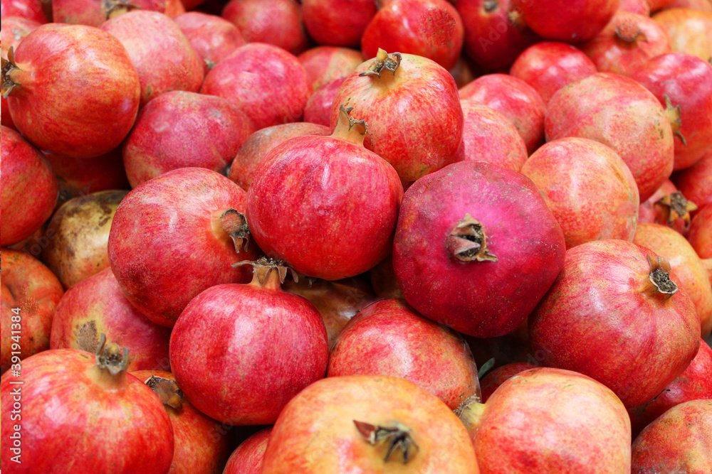 Pomegranate fruit background pattern. Whole pomegranate with flower. Fresh raw organic pomegranate fruit heap texture background. Ruby natural pomegranate close-up top view. on the market Pomegranate fruit background pattern. Whole pomegranate with flower. Fresh raw organic pomegranate fruit heap texture background. Ruby natural pomegranate close-up top view. on the market