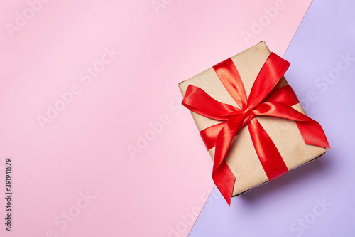 Christmas or New Year gift box with red ribbon on a colorful background