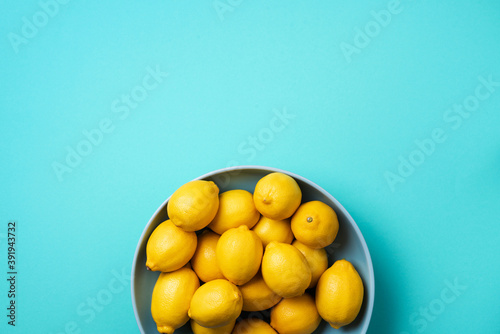 Fresh lemon fruits on plate over blue background. Top view. Copy space. Citrus fruits. Vitamins for health. Liposomal vitamin C