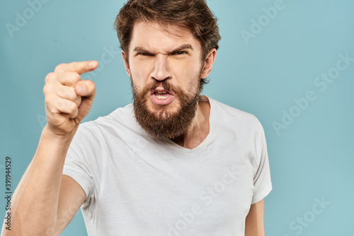 Man gestures with his hands emotions displeasure white t-shirt blue background