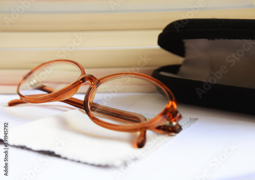 Eyeglasses with black case and cloth in front of several books