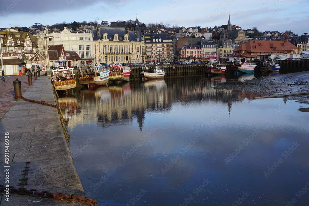 mirror reflection of boats in the harbour and the town of Trouville, France