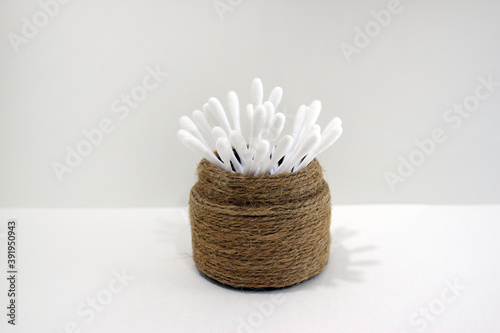 a cotton swab on a white background and in a natural twine case.