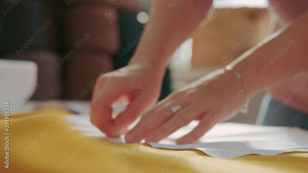 Seamstress applies the pattern to the bright yellow fabric. Close up Seamstress applies the pattern to the bright yellow fabric. Close up