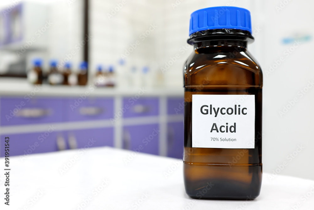 Selective focus of glycolic acid liquid solution in dark brown glass bottle in a white chemistry laboratory background. Chemical peel for skincare research Selective focus of glycolic acid liquid solution in dark brown glass bottle in a white chemistry laboratory background. Chemical peel for skincare research