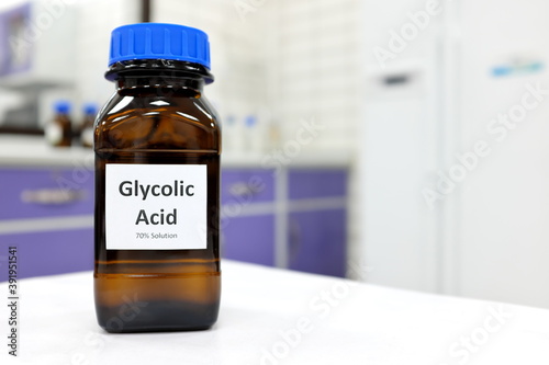 Selective focus of glycolic acid liquid solution in dark brown glass bottle in a white chemistry laboratory background. Chemical peel for skincare research photo