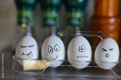 Funny smiling faces on chicken eggs. Four eggs in a box on a blurred background. Types of temperaments. Sanguine, choleric, phlegmatic and melancholic. photo