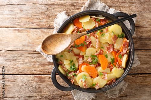 Welsh stew potatoes with bacon, onions and carrots close-up in a frying pan on the table. horizontal top view from above photo