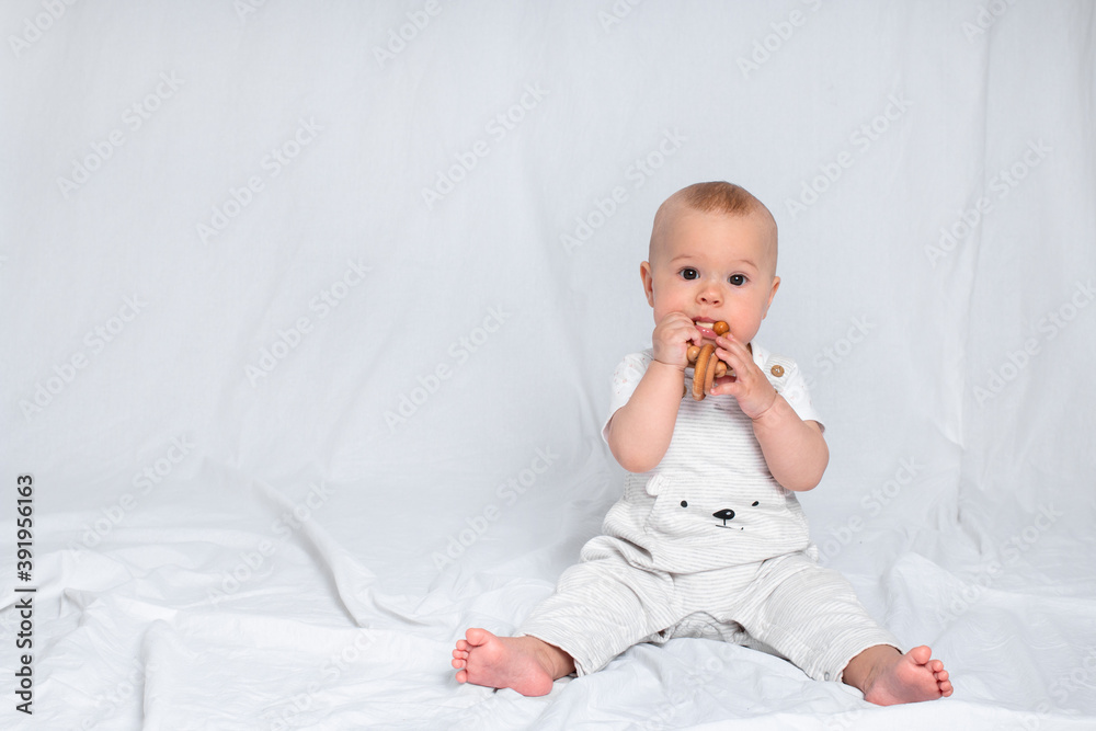 The child sits on a white background and looks ahead. Kid in light clothes for advertising. The child sits on a white background and looks ahead. Kid in light clothes for advertising.
