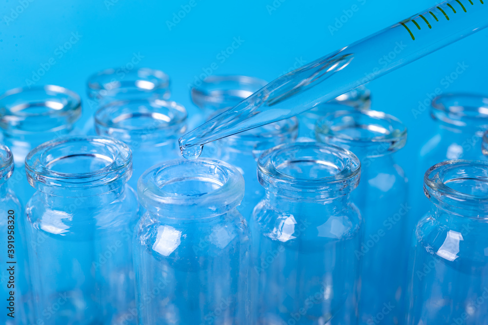 Dropping reagent on glass flask on blue background, closeup. Farmacy and medical concept background Dropping reagent on glass flask on blue background, closeup. Farmacy and medical concept background
