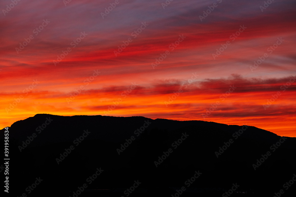 Colorful red sunset. Aesthetic red cloudy sunset in mountains. Dark silhouette mountains and orange-red sunset clouds Colorful red sunset. Aesthetic red cloudy sunset in mountains. Dark silhouette mountains and orange-red sunset clouds