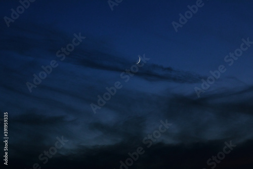 Moon sickle with dark clouds in the gloomy sky after sunset. Moon sickle with clouds for Photoshop and design. © Tengyart