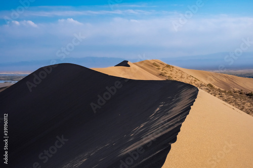 Sand dunes with clouds backgorund. Natural landscape. Altyn-Emel singing dunes or barkhan. Altyn-emel national park in Kazakhstan. Tourism travel in Kazakhstan concept.