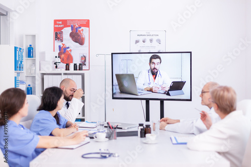 Medical staff talking with expert doctor during webinar in hospital conference room. Medicine staff using internet during online meeting with expert doctor for expertise.