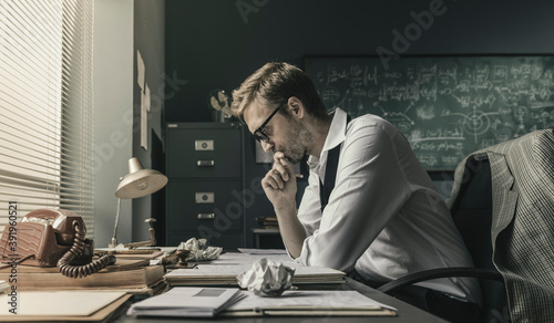 Obraz na płótnie Brilliant mathematician sitting at desk and studying math formulas