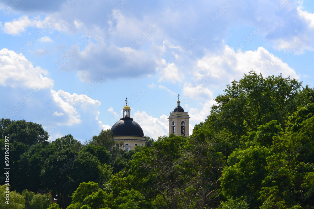 Domes of Peter and Paul Cathedral towering over the treetops and beautiful blue cloudy sky on the background. Gomel, Belarus.