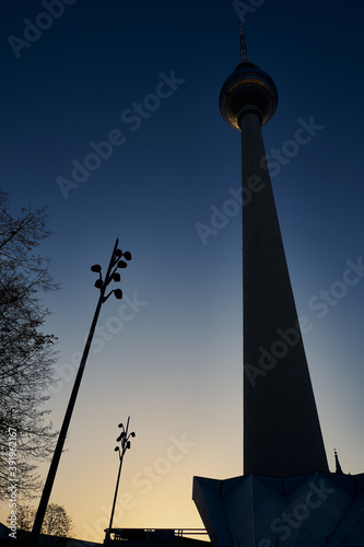 Silhouette des Fernsehturms mit Stra  enlaternen am Berliner Alexanderplatz im Gegenlicht der untergehenden Abendsonne
