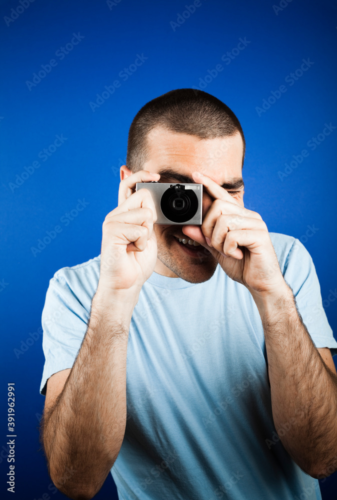 Man with dark short hair holding a small digital point and shoot camera. Man with dark short hair holding a small digital point and shoot camera.