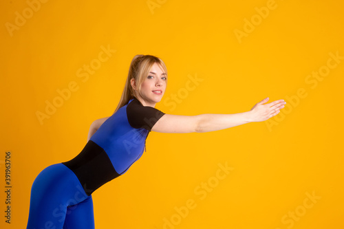 Young woman in sports clothes doing side bends on white isolated background. Side view.Fit girl living an active lifestyle. © Ilnur