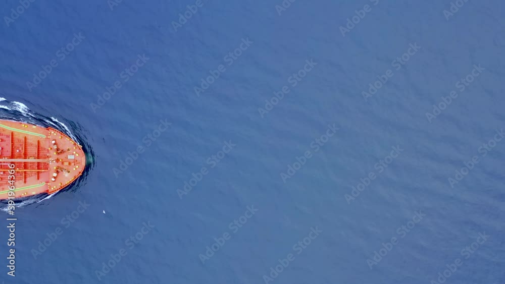 Aerial top down view of a cargo container ship sailing through the picture over blue ocean Aerial top down view of a cargo container ship sailing through the picture over blue ocean