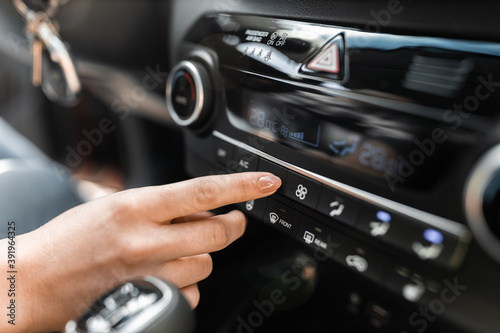 Interior view of a modern new car. Woman's hand and climatronic or air conditioner system concept.