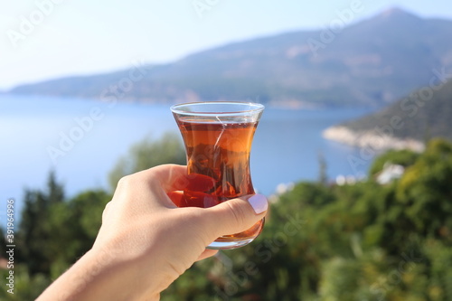 Selective focus hand holding cap of Turkish tea in Kalkan Turkey.