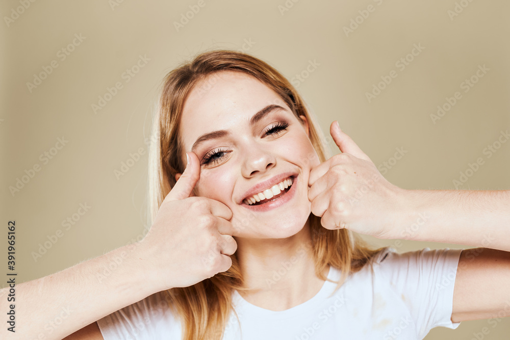 Cheerful woman in a white T-shirt gestures with her hands emotions beige background