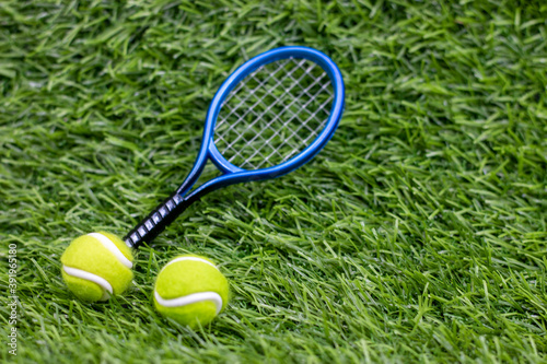 Tennis ball with racket on green grass