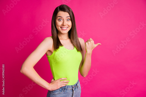 Photo of excited young girl indicate thumb empty space shiny toothy smile wear green top isolated vivid pink color background