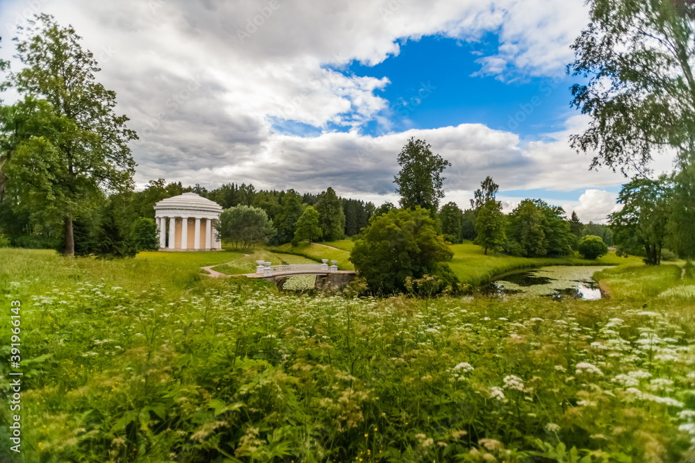 Summer landscape in the city Park with trees, pavilion, stone bridge over the river, sky with clouds Summer landscape in the city Park with trees, pavilion, stone bridge over the river, sky with clouds
