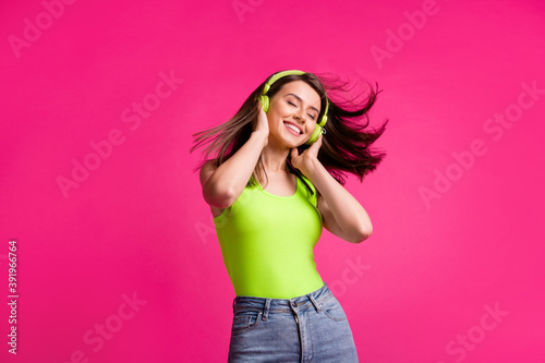 Photo of young girl fly wind hair listen music headphones enjoy happy isolated over pink color background