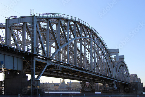 Railway double-track bridge with four arched trusses and a central lifting span in the counterlight © Elena