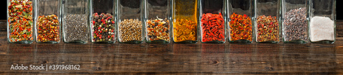 A mixture of various spices in a glass jar close up. Spices and condiments on a black, old shabby board. Free space and copy space for text near condiments.