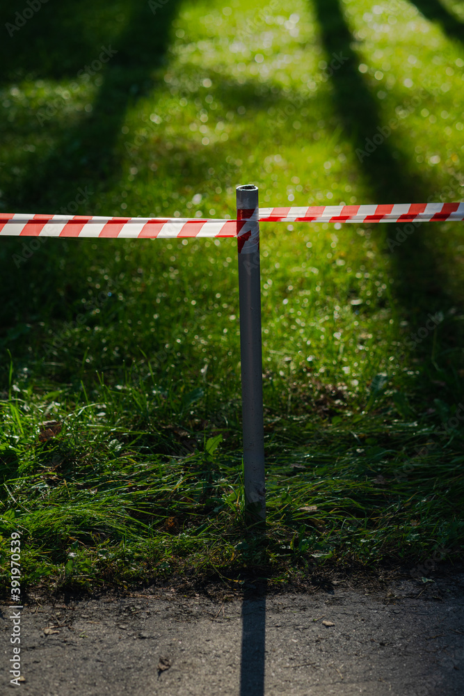 A barrier tape separates the natural landscape from the asphalt road. The forest park zone is prohibited. The entrance to the beautiful sunlit lawn in the forest is closed. Respect for nature concept. A barrier tape separates the natural landscape from the asphalt road. The forest park zone is prohibited. The entrance to the beautiful sunlit lawn in the forest is closed. Respect for nature concept.