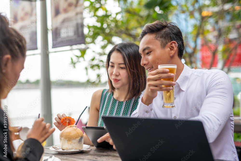 Business meeting outdoor. Two asian women and one asian man seated at a restaturant table