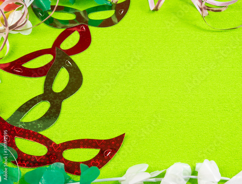 Brazilian carnival masks and props arranged on green background, top view